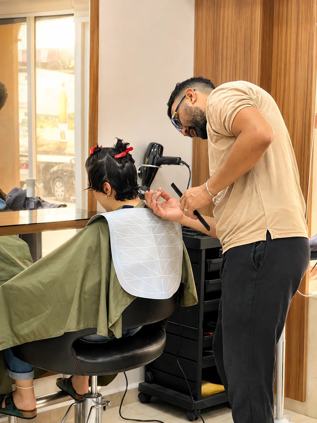 Un coiffeur travaille dans le Salon Casoria, devant un miroir encadré de bois clair